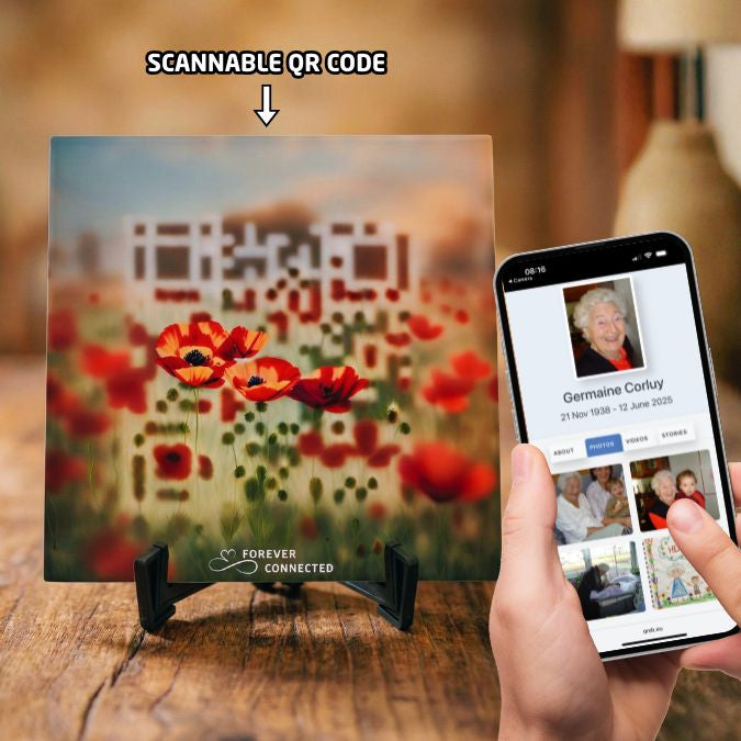 A  ceramic tile resting on a black stand, featuring red poppies with an embedded QR code that leads to a  digital memorial website.