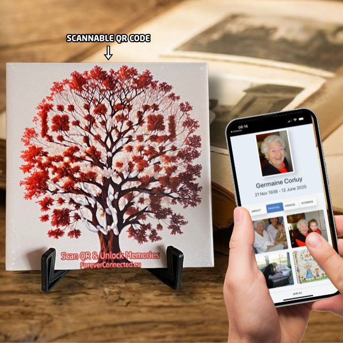 A white ceramic tile resting on a black stand, featuring a red "Tree of Life" illustration with an embedded QR code for unlocking digital memories.